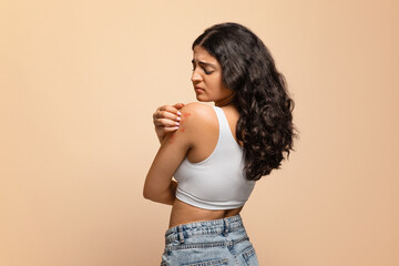 Annoyed young indian woman scratching her irritated body skin - obrazy, fototapety, plakaty