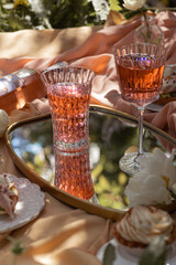 Closeup two glass of rose wine , picnic basket, food and flowers on the spring blossom garden.