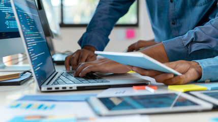 Web developers reviewing and debugging code together on a desktop computer, with notepads and digital tablets on the desk, business technology, with copy space