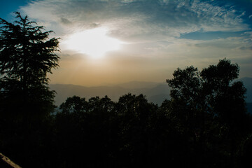Fototapeta na wymiar Sunset view from the mountains of Lansdowne. Mountain Sunset view in Lansdowne. Amazing golden sunset seen through forest drive, Lansdowne Uttarakhand.
