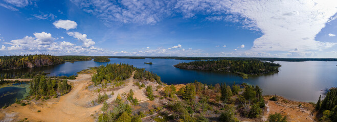 Aerial view of an abandoned polluted mine site next to a beautiful northern lake. The ground is...