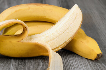 bananes avec épluchure sur fond bois - 751565174