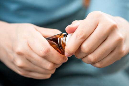 A woman's hand opens a bottle of medicine, vitamins or nutritional supplements. Caring for the health of older people.