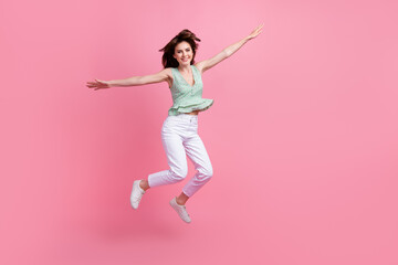 Photo of cheerful overjoyed girl have fun fly in air with open arms isolated on pink color background