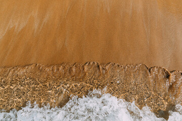 sandy beach with waves rolling in, creating a beautiful natural landscape. The beige sand contrasts...