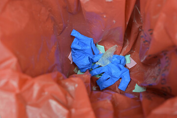Blue gloves and operating room waste are discarded in red infectious waste bags.