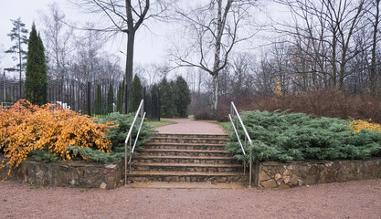 stone steps with metal railings between green bushes in an autumn park
