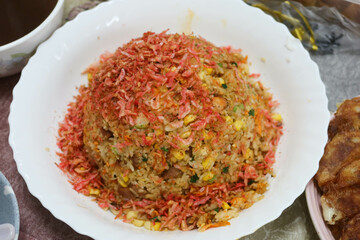 homemade an egg fried rice with sakura prawns as toppings in a white plate