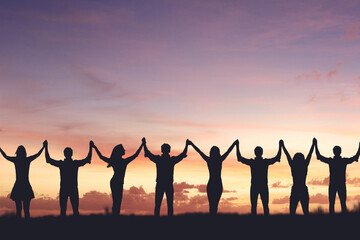 Fototapeta premium Silhouette of people holding hands against sunset background, concept of peace and victory