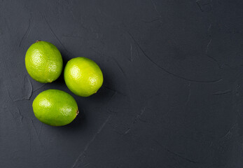 Three lime fruits on a dark background