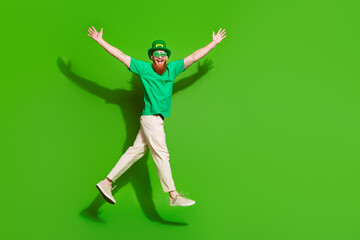 Full size profile photo of crazy charismatic person jump raise arms empty space isolated on green...