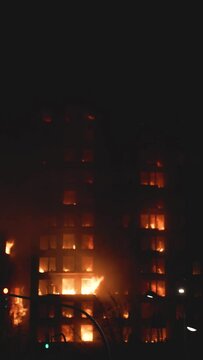A large fire in a residential building at night. View of the facade with fire in its windows with great virulence. Fire in the dead of night