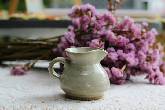 A small ceramic jug on purple flower background