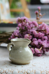 A small ceramic jug on purple flower background