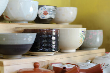 Ceramic sets displayed on wooden shelves.
