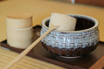 A bamboo ladle on the ceramic bowl of a traditional Japanese matcha tea set.