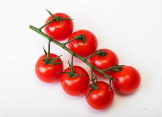 Red tomatoes on a green twig on white background
