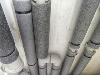 Close-up of insulated plumbing pipes. Insulated Pipes in Public Restroom