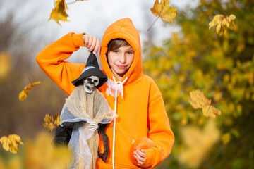A child in an orange costume and a wizard hat for Halloween. A boy holds a skeleton at a Halloween...