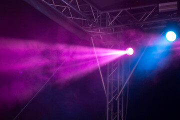 A white smoky beam of light from a stage spotlight on a purple dark background. Part of the stage...