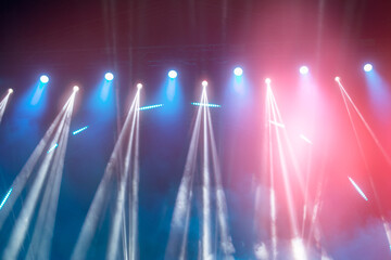 Abstract blue-pink background with white smoky rays of light from stage spotlights.