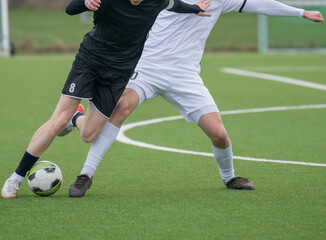 Fußballspieler auf einem Kunstrasen im Zweikampf beim Fußballspielen