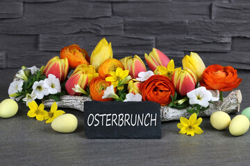 Der Text Osterbrunch auf eine Kreidetafel geschrieben mit Blumen und Ostereiern.
