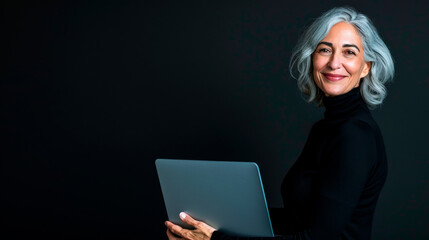 Portrait of an adult woman in a black turtleneck with a laptop in her hands on a black isolated background with space for text.