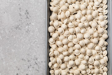 Frozen raw mini dumplings on a gray background. copy space