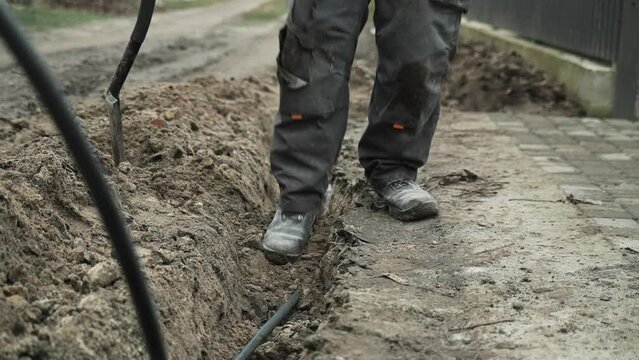 Worker Digs electric wires into the ground with a Shovel	
Man digs a ditch in the ground with a shovel