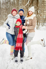 Happy family of four stands embracing on skates on ice pathway in winter park