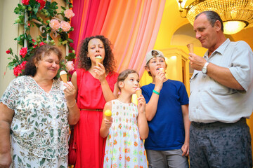 Happy grandmother, grandfather, mother and children eating ice cream in store