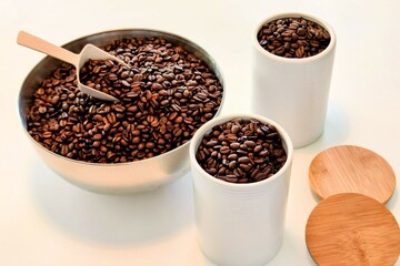 Freshly roasted coffee beans from a bowl being refilled in jars for storage.
