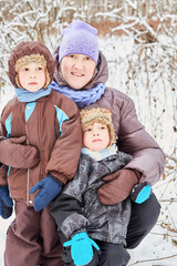 Portrait of mother and two little sons in winter snowy park