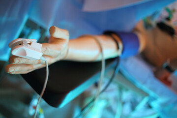 Dummy hand with a sensor for pulse oximetry on finger on the surgical table