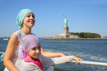 Portrait of mother with daughter on a boat in front of the famous Statue of Liberty in New York