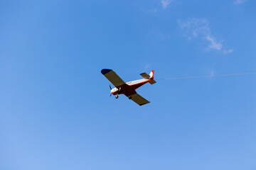 Small glider plane puller against the blue sky. A shot of a small airplane used to pull sailplanes up in the sky.