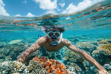 Foto auf Acrylglas Man snorkeling over a coral reef in clear blue water. © evgenia_lo