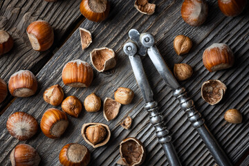 Hazelnuts with a classic silver nutcracker on wooden table. Food photography