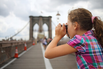 Girl takes pictures on the Brooklyn Bridge, side view
