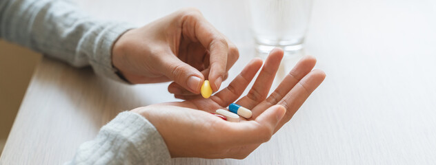 Healthcare Harmony: Close-Up Hands Holding Medication and Water Glass for Optimal Wellness,...