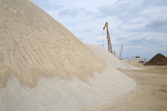 Cranes at dock on River and huge piles of sand at spring day