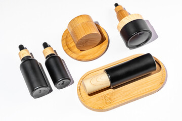 Set of cosmetic products in black and bamboo glass package. Beauty oil in dropper bottle and jars with cream for healthy skin. Unbranded package for cosmetics promotion. Knolling style, top view