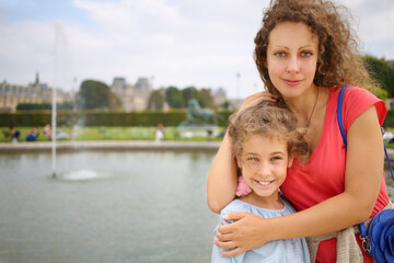 Fototapeta na wymiar Portrait of a beautiful woman and girl in a park near the fountain in Paris