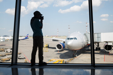 Silhouette of a boy photographing a plane through the window of Airport