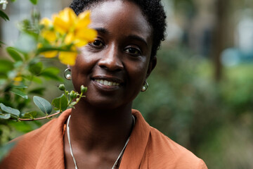 Smiling black woman looking at camera beside blurred flower.