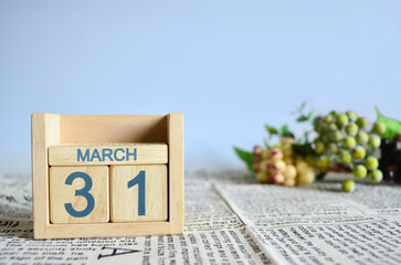 March 31, Calendar cover design with number cube with fruit on newspaper fabric and blue...