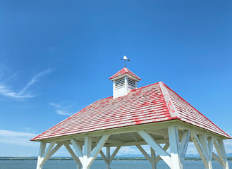 Faded red wooden roof with bell tower and weather vane to indicate wind direction. Pergolas in a...