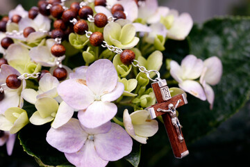 Prayer beads on flowers. Crucifix with Jesu. Catholic sympbol.