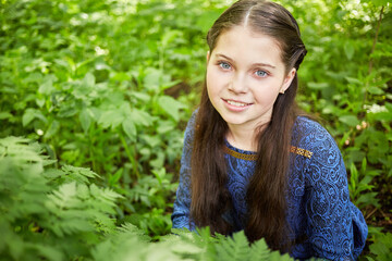 Portrait of smiling teenage girl among foliage in summer park